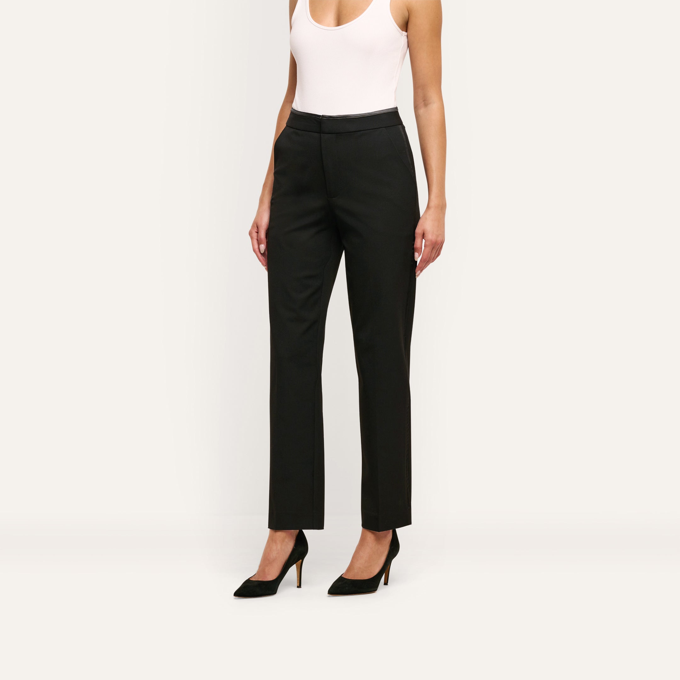 A person wearing a white tank top and Rebel Trouser slim-straight black trousers in stretch twill suiting with pointed-toe heels.