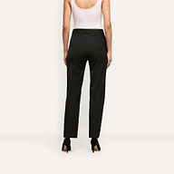 A person viewed from behind wearing slim-straight, black stretch twill Rebel Trouser suiting trousers and black high-heeled pumps.