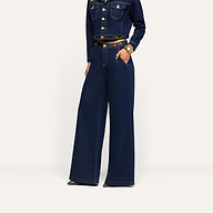 A person wearing a cropped dark-wash denim jacket and matching Jules Wide-Leg Jean with gold-tone horsebit hardware at the waist.
