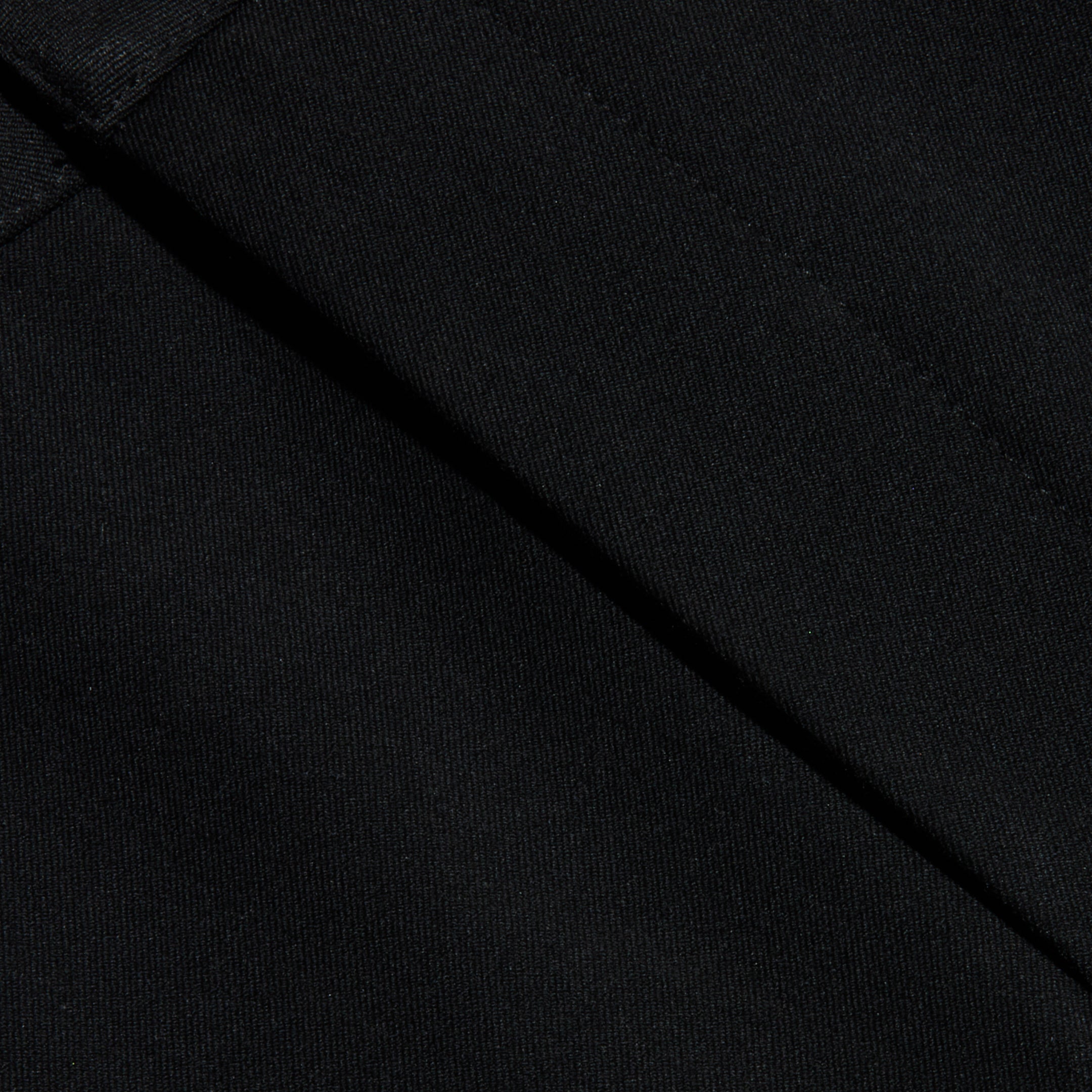Close-up of black fabric with visible diagonal seams, showcasing the texture and stitching detail of the Colby Barrel-Leg Trouser.