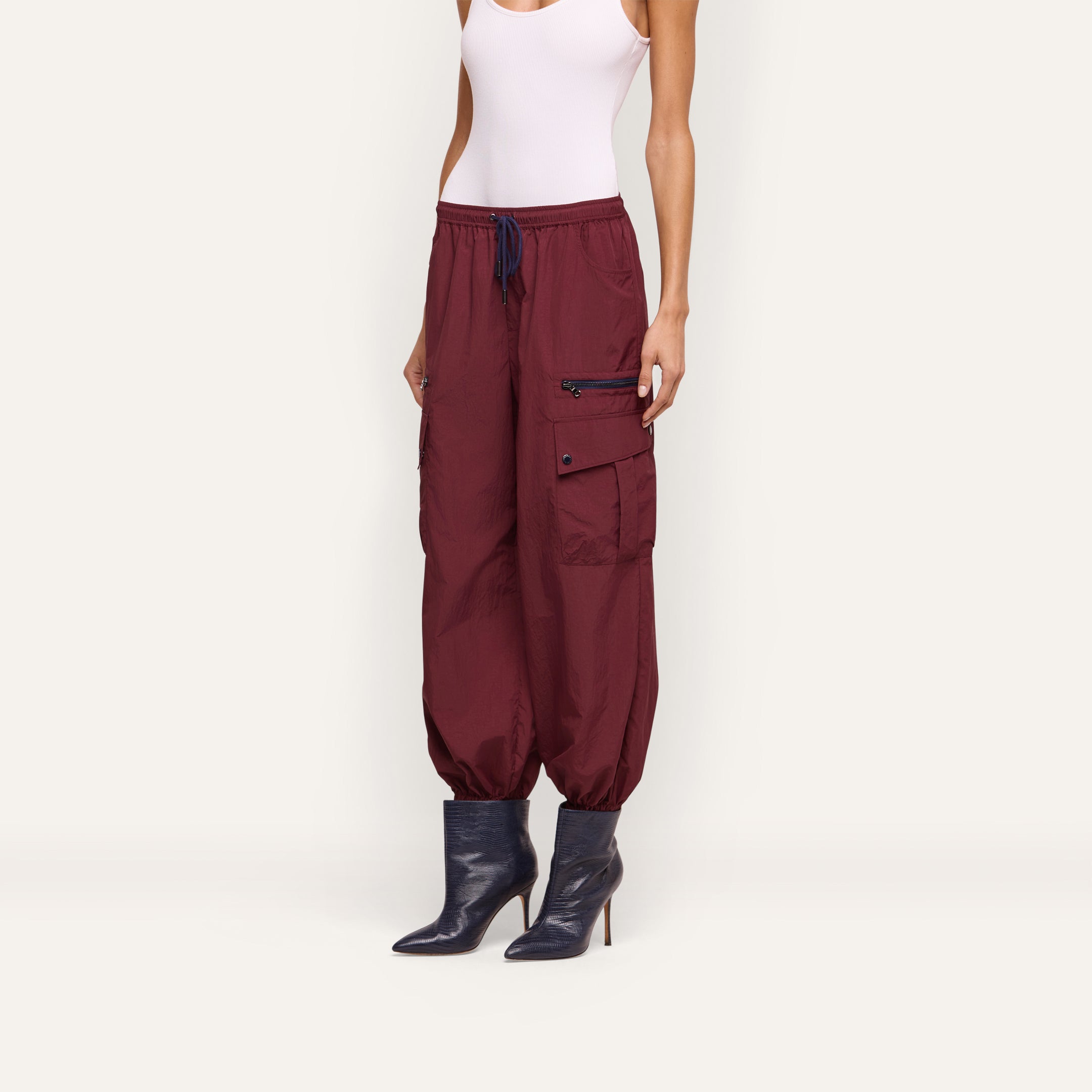 Monrose Nylon Jogger in maroon water-repellant nylon with a drawstring waist, side utility pockets, and cinched cuffs, worn with dark blue pointed-toe heeled boots.
