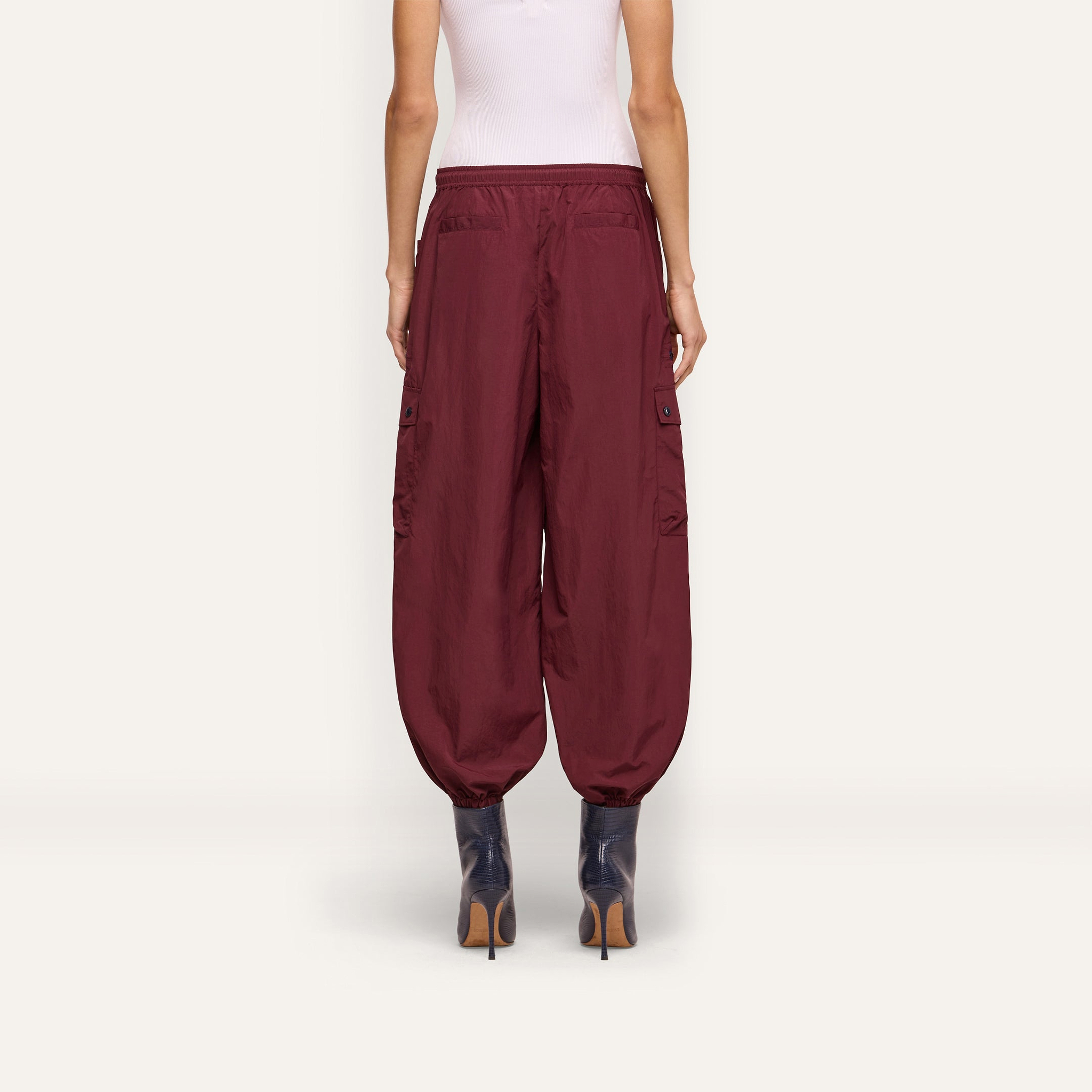 Back view of a person wearing dark red Monrose Nylon Jogger cargo pants with side utility pockets and cinched cuffs, paired with dark heeled boots.