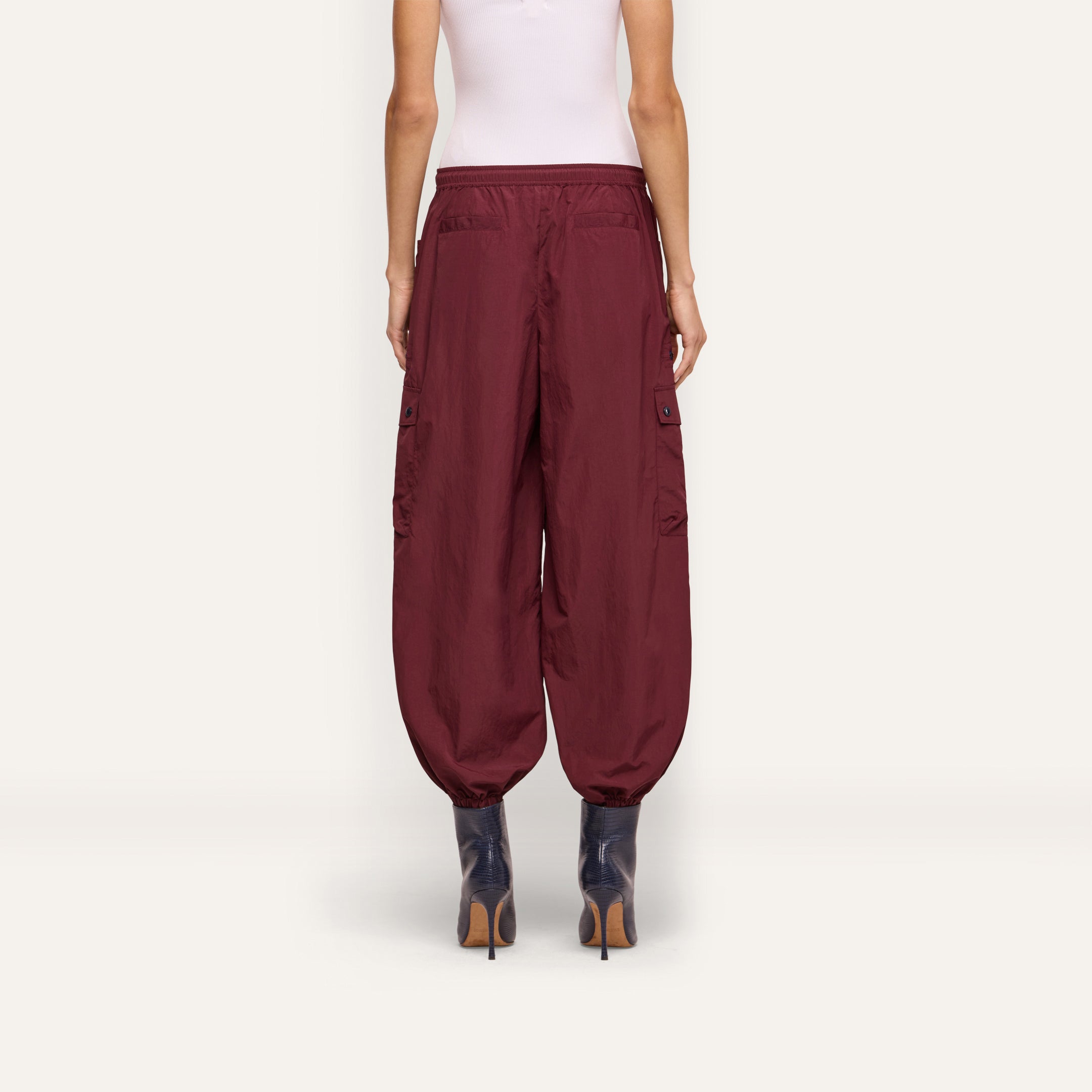 Back view of a person wearing dark red Monrose Nylon Jogger cargo pants with side utility pockets and cinched cuffs, paired with dark heeled boots.