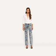 A woman wears a white button-down shirt tucked into Gianna Stovepipe Jean low-rise, slim jeans featuring an intricate, multicolored floral print.