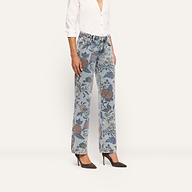 A person wears Gianna Stovepipe Jean in light-wash, low-rise, slim-fit denim with a floral print, paired with a white button-down shirt and dark high heels.