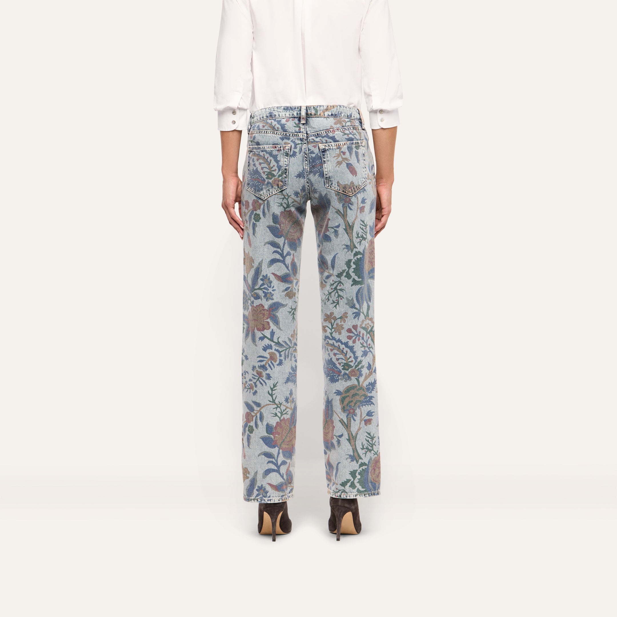 Back view of the Gianna Stovepipe Jean in a low-rise, light-wash slim fit with an all-over floral and paisley print, paired with a white button-down shirt and brown heeled boots.