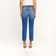 A person stands with their back to the camera, wearing a white sleeveless top, beige heels, and the Avena Slim-Leg Jean in a blue high-rise slim-cut denim style against a plain light background.