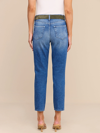 A person stands facing away, wearing the Avena Slim-Leg Jean—a pair of blue high-rise jeans with a wide green waistband—paired with a white sleeveless top and beige heeled sandals, against a plain beige background. The Avena Slim-Leg Jean offers a flattering silhouette with its slim-cut design while preserving the structured look of non-stretch denim.