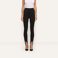 A person wearing black Enid Stirrup Leggings in a high-waisted scuba knit fabric paired with black pointed-toe heels.