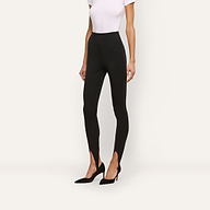 A person wearing high-rise, black scuba knit Enid Stirrup Legging and black pointed-toe heels.