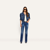 A woman wearing a dark blue denim jacket over a white top, and Kezia Bootcut Jean low-rise stretch jeans with a black belt.
