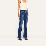 A person wears a beige tank top and Kezia Bootcut Jean low-rise jeans with a black belt and dark pointed-toe heels.