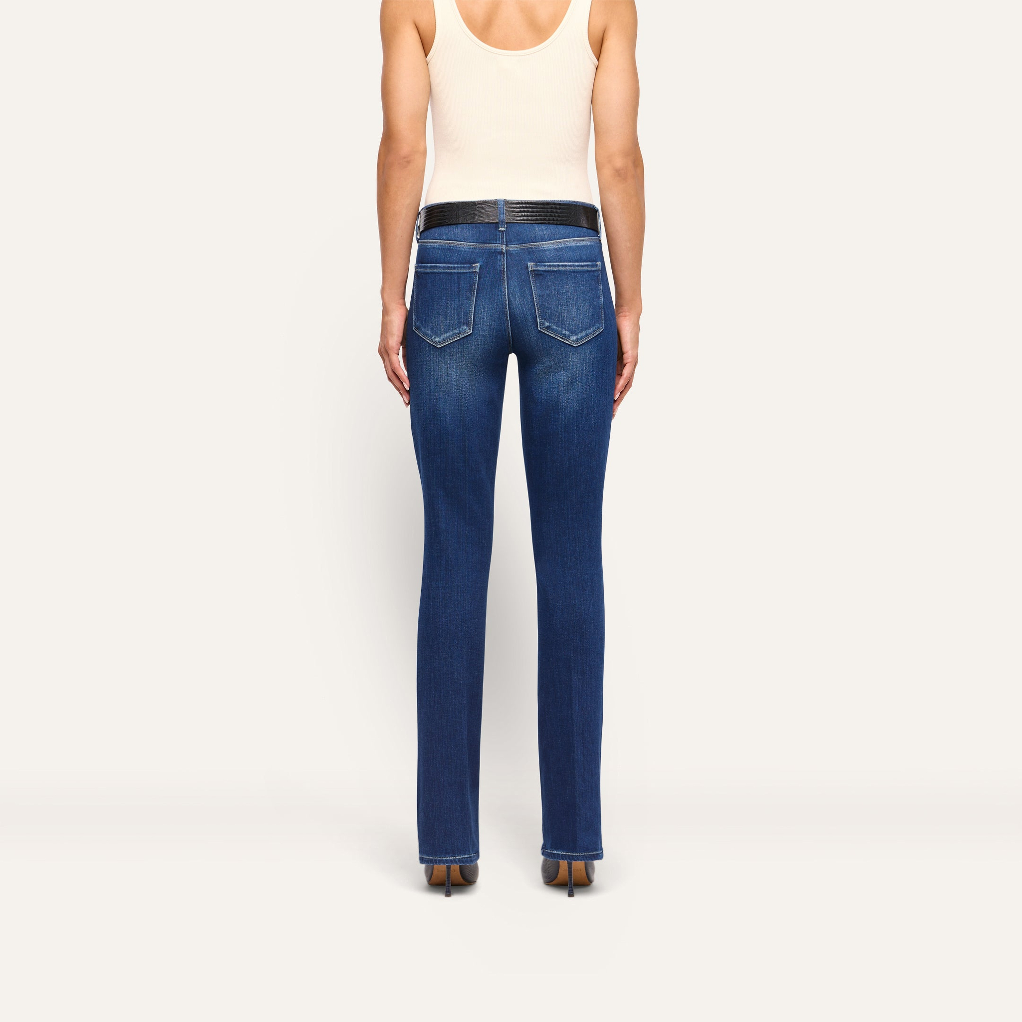 Back view of a person wearing Kezia Bootcut Jean in dark-wash with a low rise and black belt.