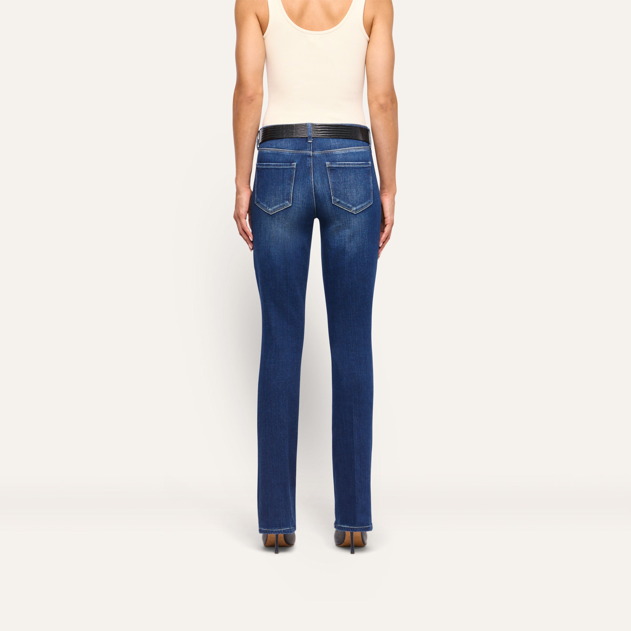 Back view of a person wearing Kezia Bootcut Jean in dark-wash with a low rise and black belt.