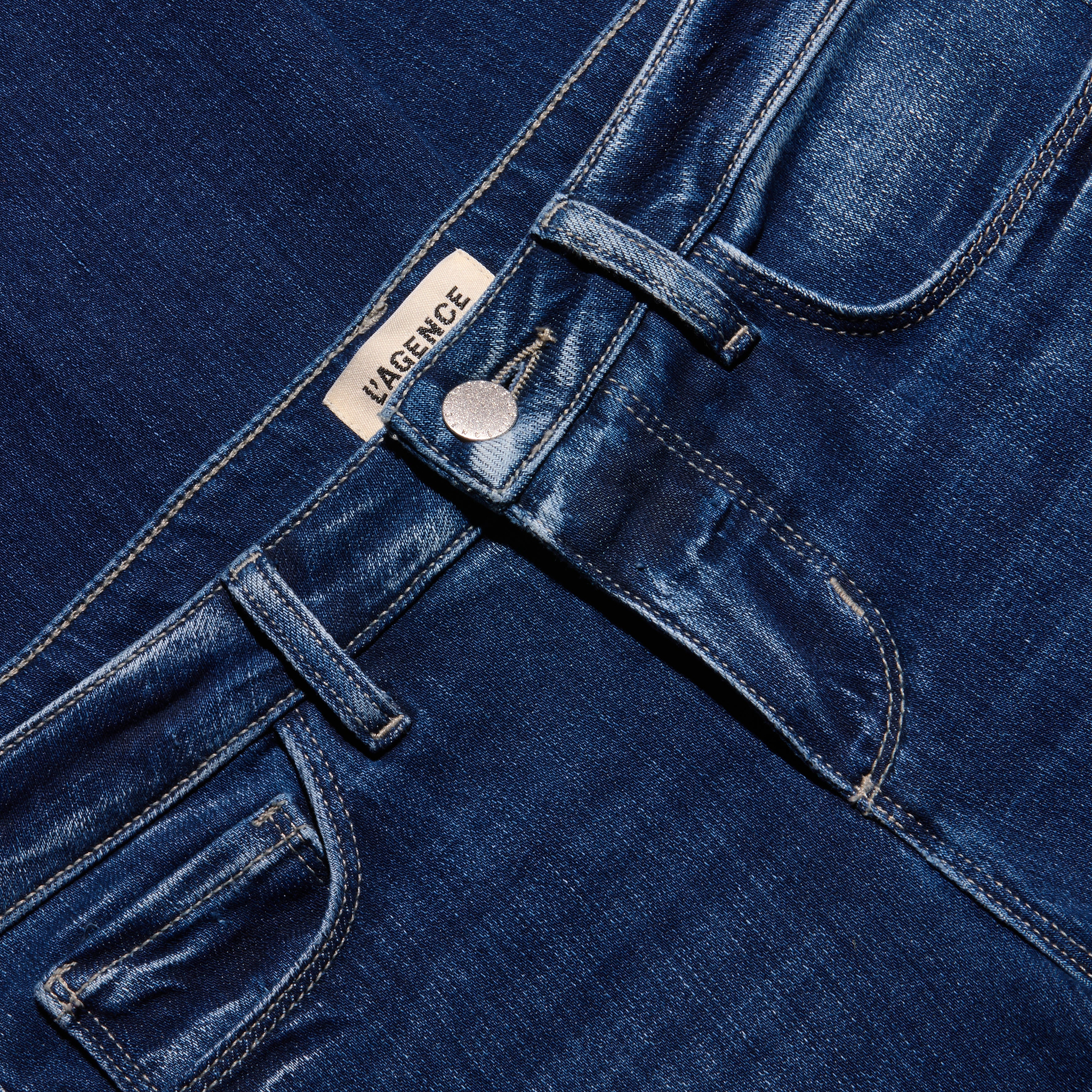 Close-up of the waistband, button closure, and pockets of the dark blue stretch denim Kezia Bootcut Jean.