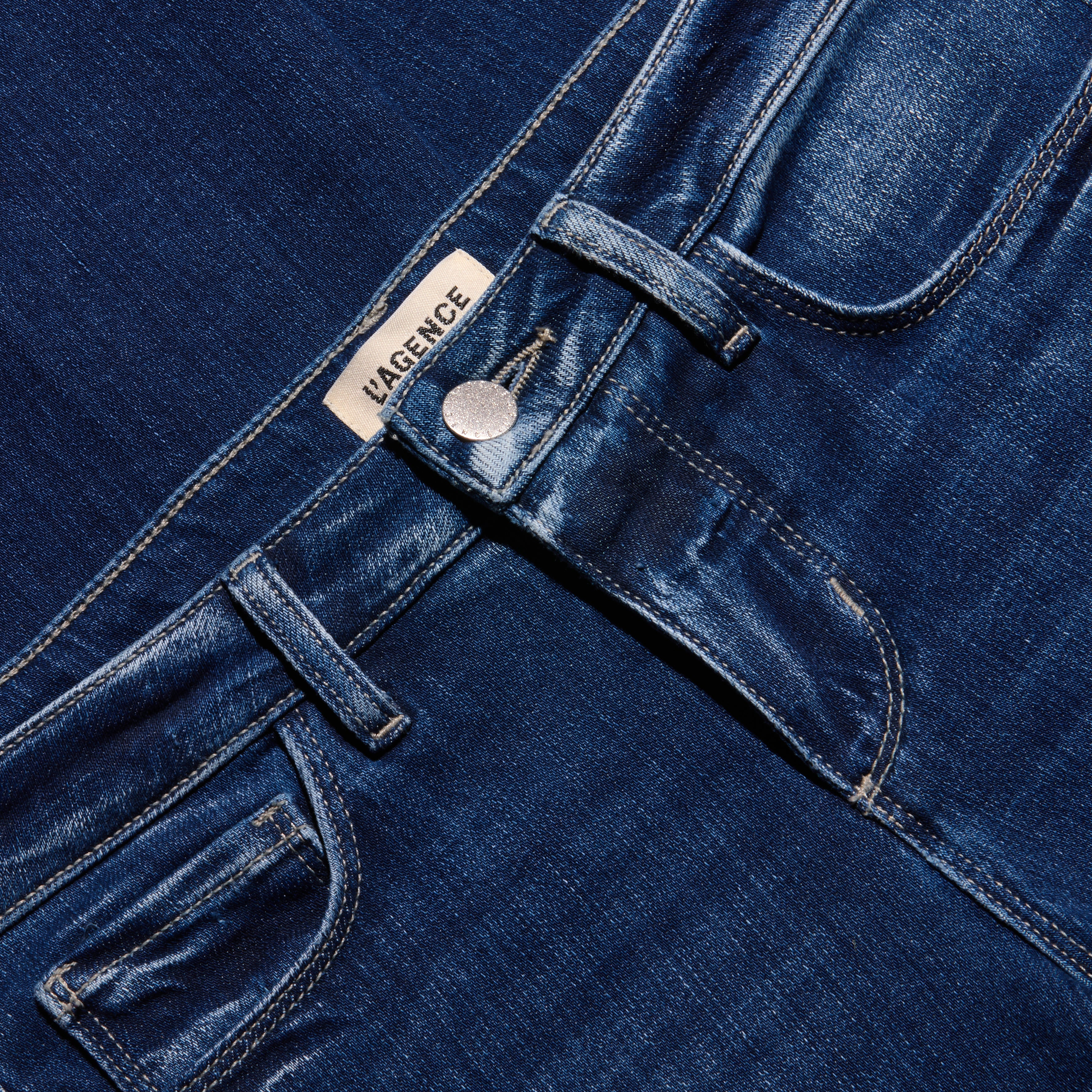 Close-up of the waistband, button closure, and pockets of the dark blue stretch denim Kezia Bootcut Jean.