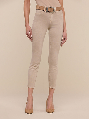 A person wearing Margot Cropped Skinny Jeans in beige with a contoured waistband, a brown belt with a silver buckle, and tan pointed-toe heels stands against a plain beige background.