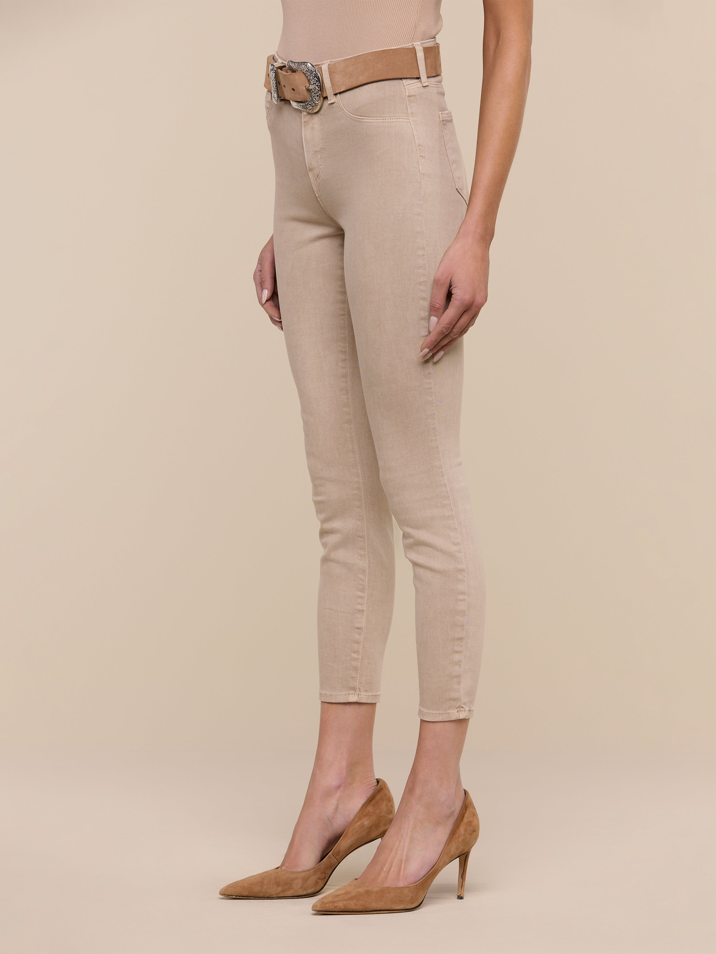 Model wearing tan high heels, Margot Cropped Skinny Jean in beige with a contoured waistband, a beige belt, and a beige sleeveless top. The photo is taken against a plain white background, showing the model from shoulder to feet.