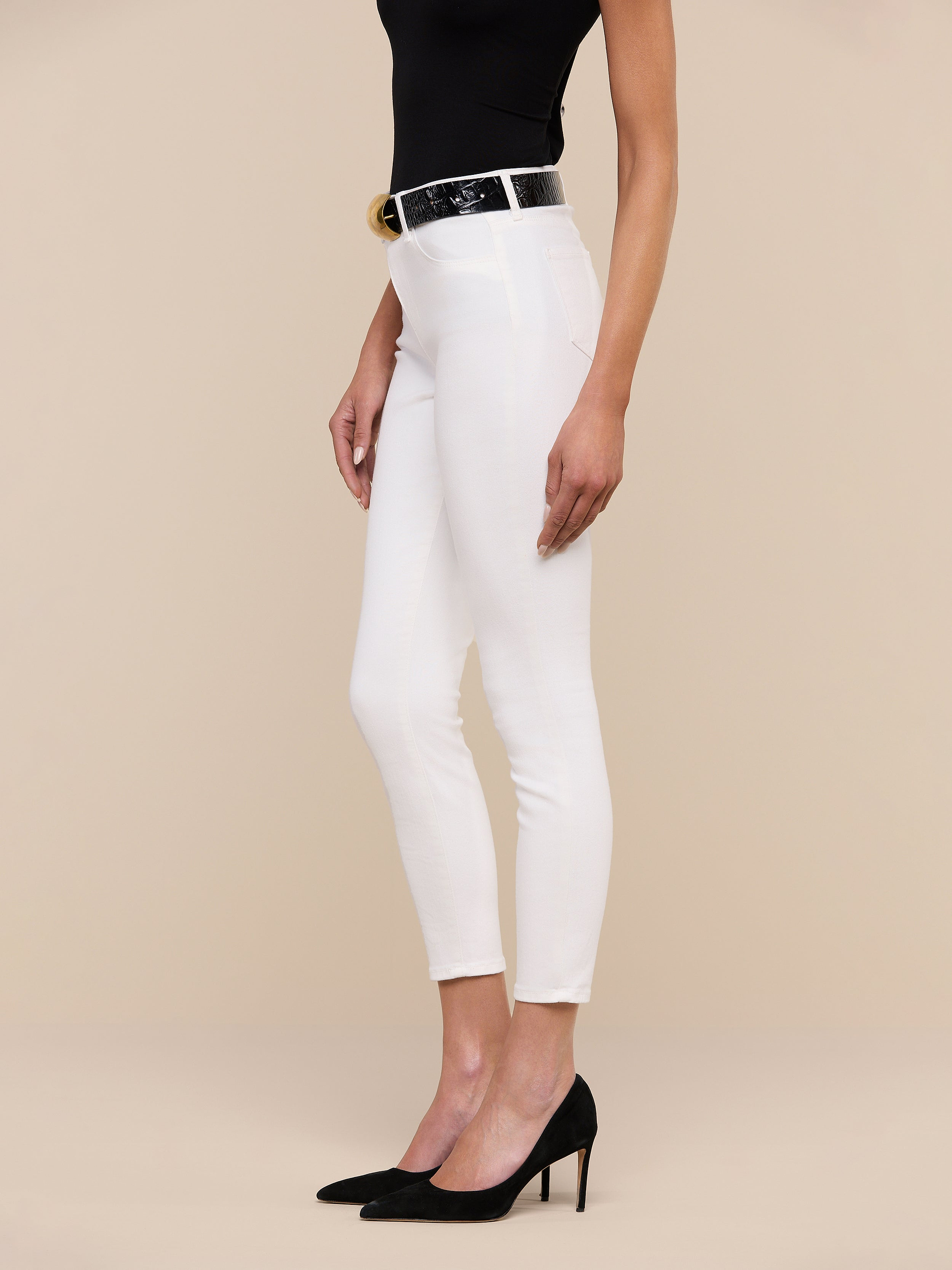 A woman in a black sleeveless top, black belt, black high heels, and the Margot Cropped Skinny Jean stands against a plain white background, shown from mid-shoulder to feet.