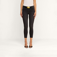 A woman stands against a plain background wearing the Margot Cropped Skinny Jean in black, featuring a contoured high-rise waistband and styled with a belt. She pairs the jeans with a white sleeveless top and black open-toe heels. Her arms are by her sides, and her head is not visible in the image.