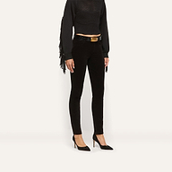 Marguerite Corduroy Skinny Pant in high-rise black corduroy with an embossed belt featuring a large gold buckle, worn with a black fringed top and black pointed-toe heels.