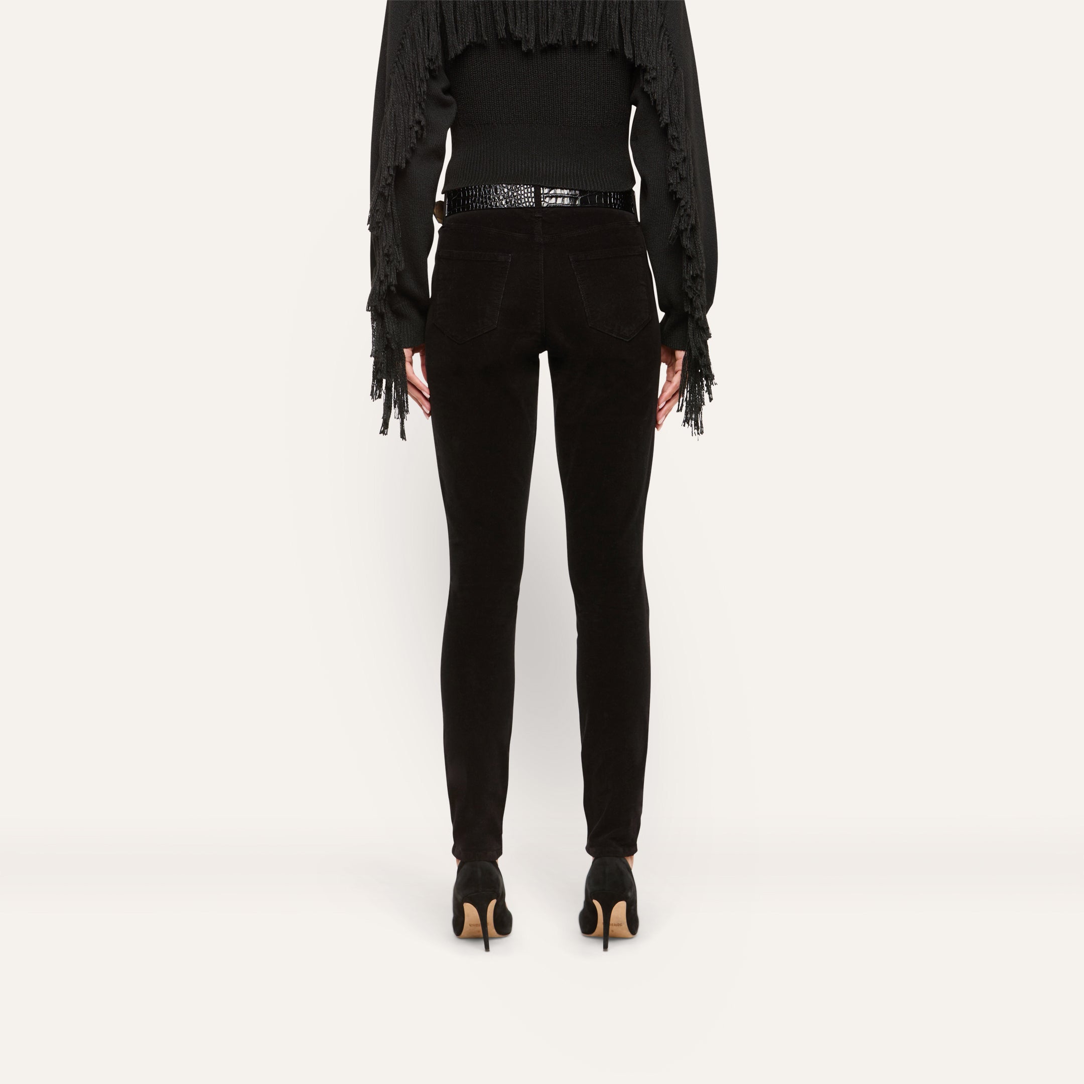 Back view of Marguerite Corduroy Skinny Pant in black, featuring a high-rise waist, a patterned belt, and black stiletto heels.