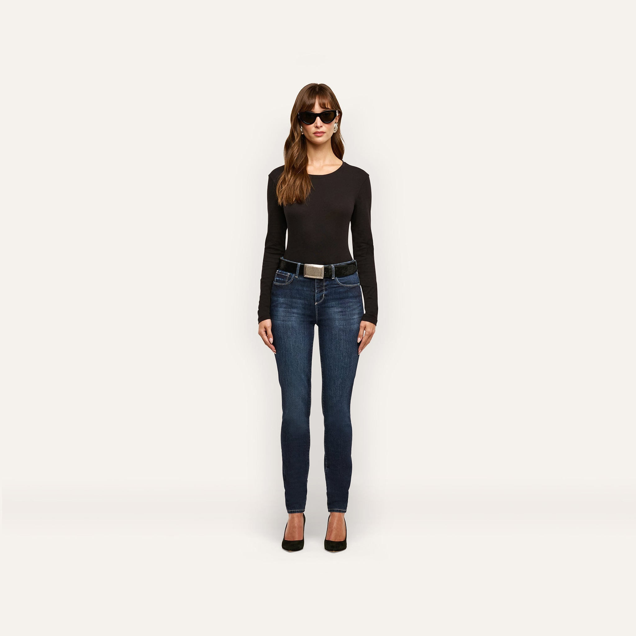 Woman wearing a black long-sleeved shirt and Marguerite Skinny Jean with a black belt and black heels.