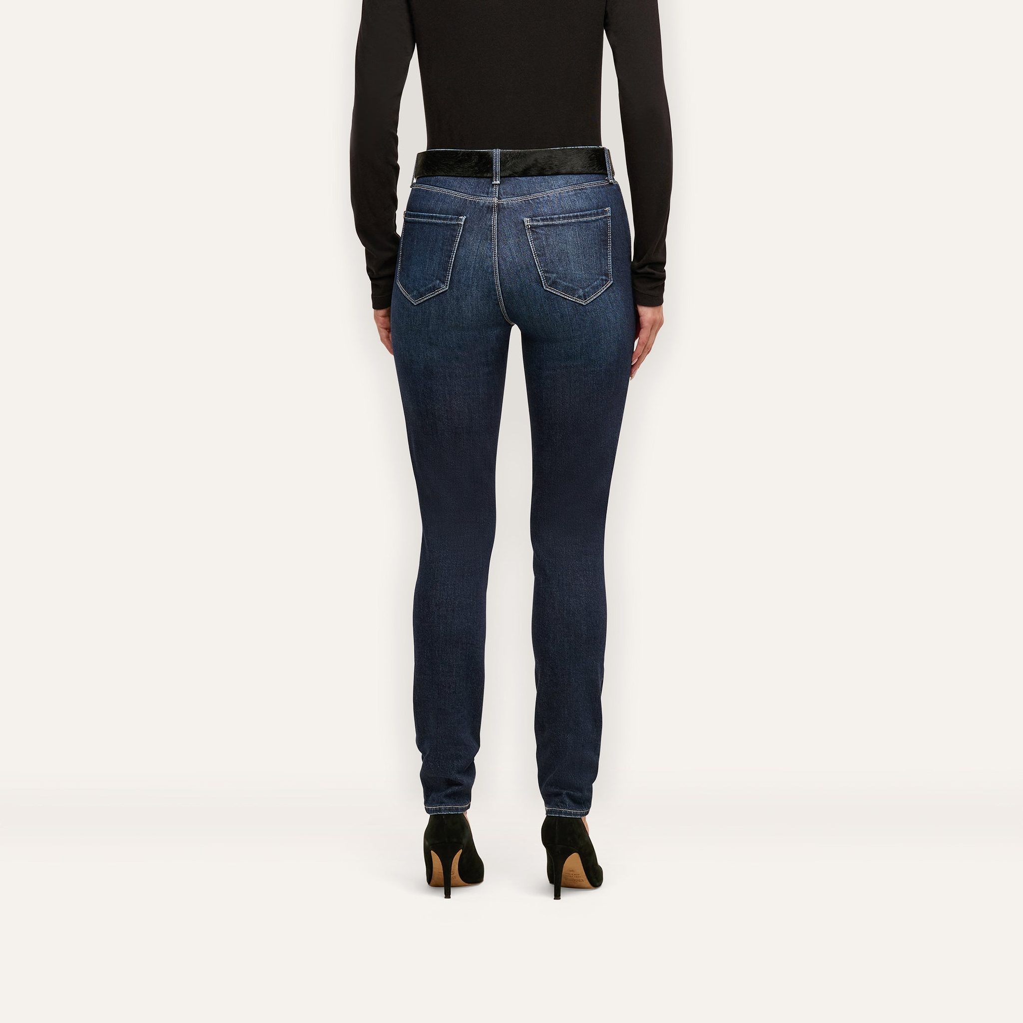 Back view of Marguerite Skinny Jean high-rise skinny jeans worn with a black top and black high-heeled pumps.