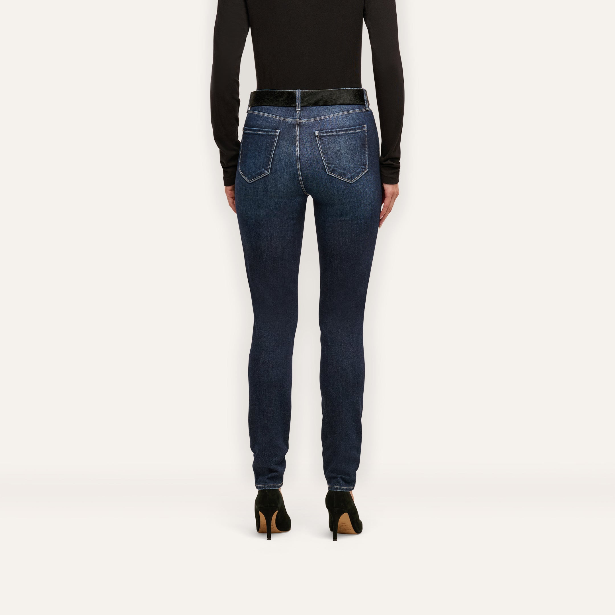 Back view of Marguerite Skinny Jean high-rise skinny jeans worn with a black top and black high-heeled pumps.