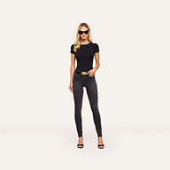 Woman wearing sunglasses, a fitted black t-shirt, Marguerite Skinny Jean with a 30-inch inseam and belt, and black heels stands against a plain light background.