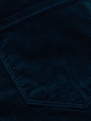Close-up of the Marguerite Velvet Skinny Jean by L'AGENCE in dark teal, featuring visible edge stitching. The image highlights the soft texture and seam details, showcasing the luxurious look typical of stretch velvet designs.