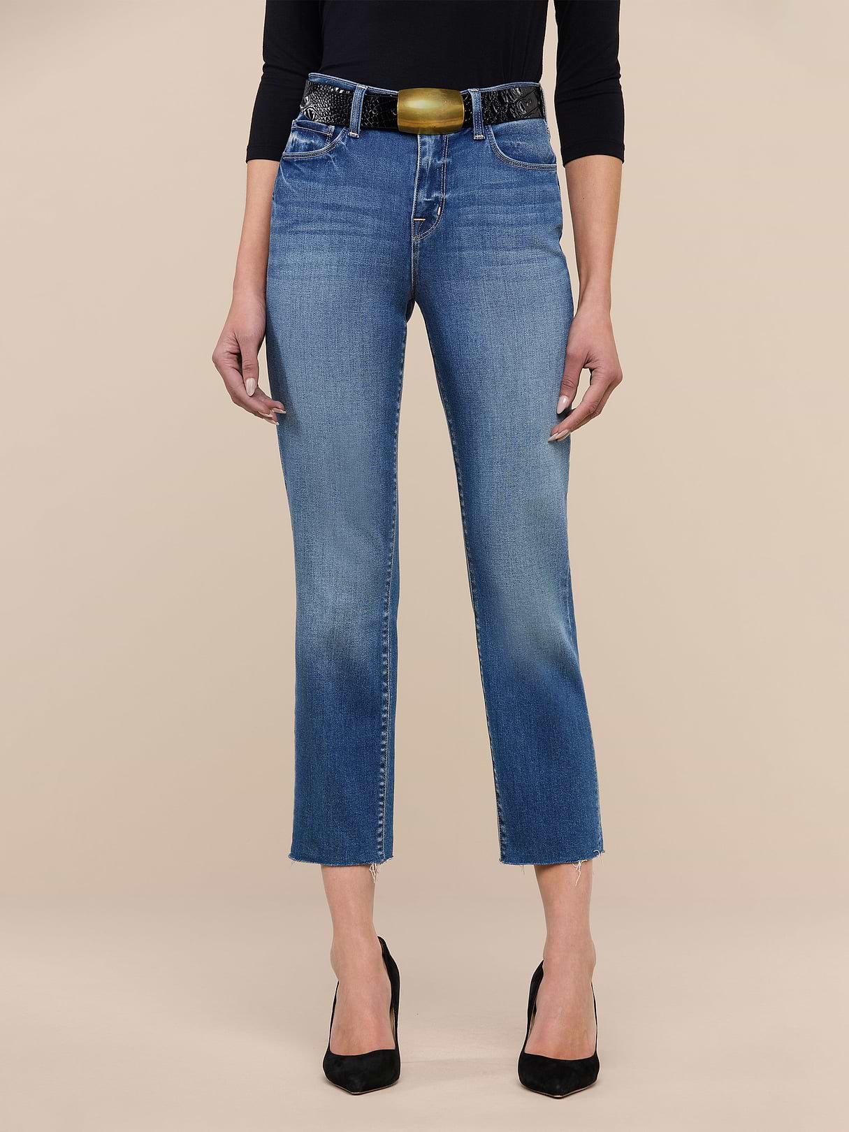 A person wearing the Sada Slim-Leg Cropped Jean, paired with black pointed heels, a black three-quarter sleeve top, and a wide belt stands against a plain white background.