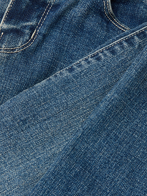 Close-up of blue Sada Cropped Slim-Leg Jean denim shows a seam and pocket. The textured stitching highlights the quality stretch fabric, combining comfort and style.