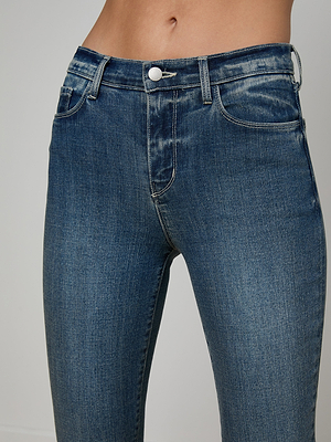 A close-up of a person’s midsection wearing the Sada Cropped Slim-Leg Jean, featuring blue stretch denim, a button closure, belt loops, and subtle fading on the thighs.