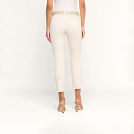 Une personne, de dos, porte un jean court Sada Slim-Leg aux ourlets effilochés, une ceinture texturée beige et des sandales à talons beiges, sur un fond beige uni.