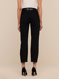 A person faces away from the camera in black Sada Slim-Leg Cropped Jeans with frayed hems, a black textured belt, black heeled shoes, and a white sleeveless top, set against a beige background.
