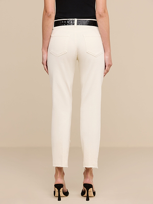 A person wearing Sada Slim-Leg Cropped Jean in off-white with frayed hems, paired with a black belt and black high-heeled sandals, shown from the back against a plain beige background.