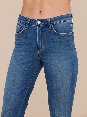Close-up of a person wearing Bell Flare Jean, vintage-inspired blue denim with button and zipper closure, set against a plain beige background. Only the torso and upper legs are visible.