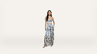Woman in a blue and white floral patterned crop top and wide-leg pants set, standing against a plain white background, with hands in her pockets and wearing sandals.