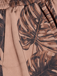 A close-up of the Lillian Satin Pant fabric, featuring a brown palm leaf print on a light pink background, highlighting the texture and detailed design.