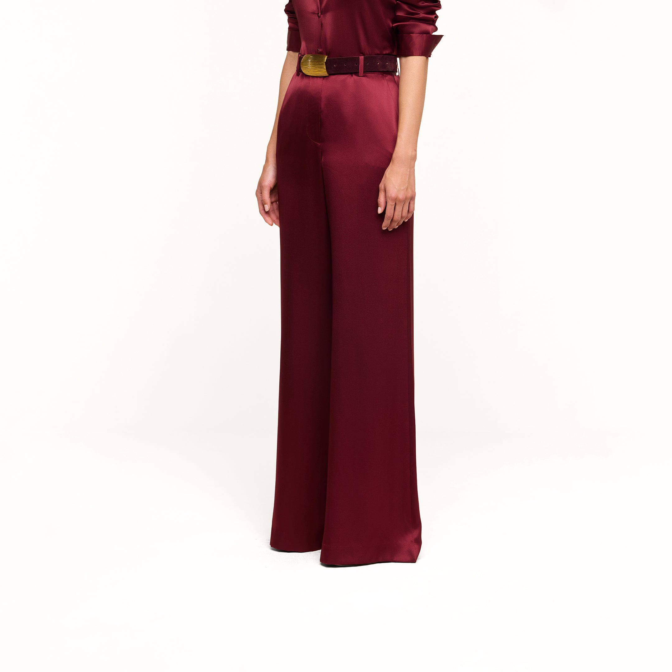 A person wearing the Pilar Silk Wide-Leg Pant in burgundy, styled with a matching belt and long-sleeve top, standing against a plain white background.