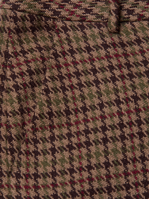 Close-up of the Pilar Houndstooth Wide-Leg Pant by L'AGENCE, featuring wool fabric in brown, green, beige, and red houndstooth with visible stitching and a waistband—ideal for a classic high-rise silhouette.