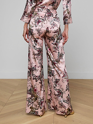 A person wearing the Pilar Silk Wide-Leg Pant in a pink, butterfly jungle print satin, shown from the back against a plain background.