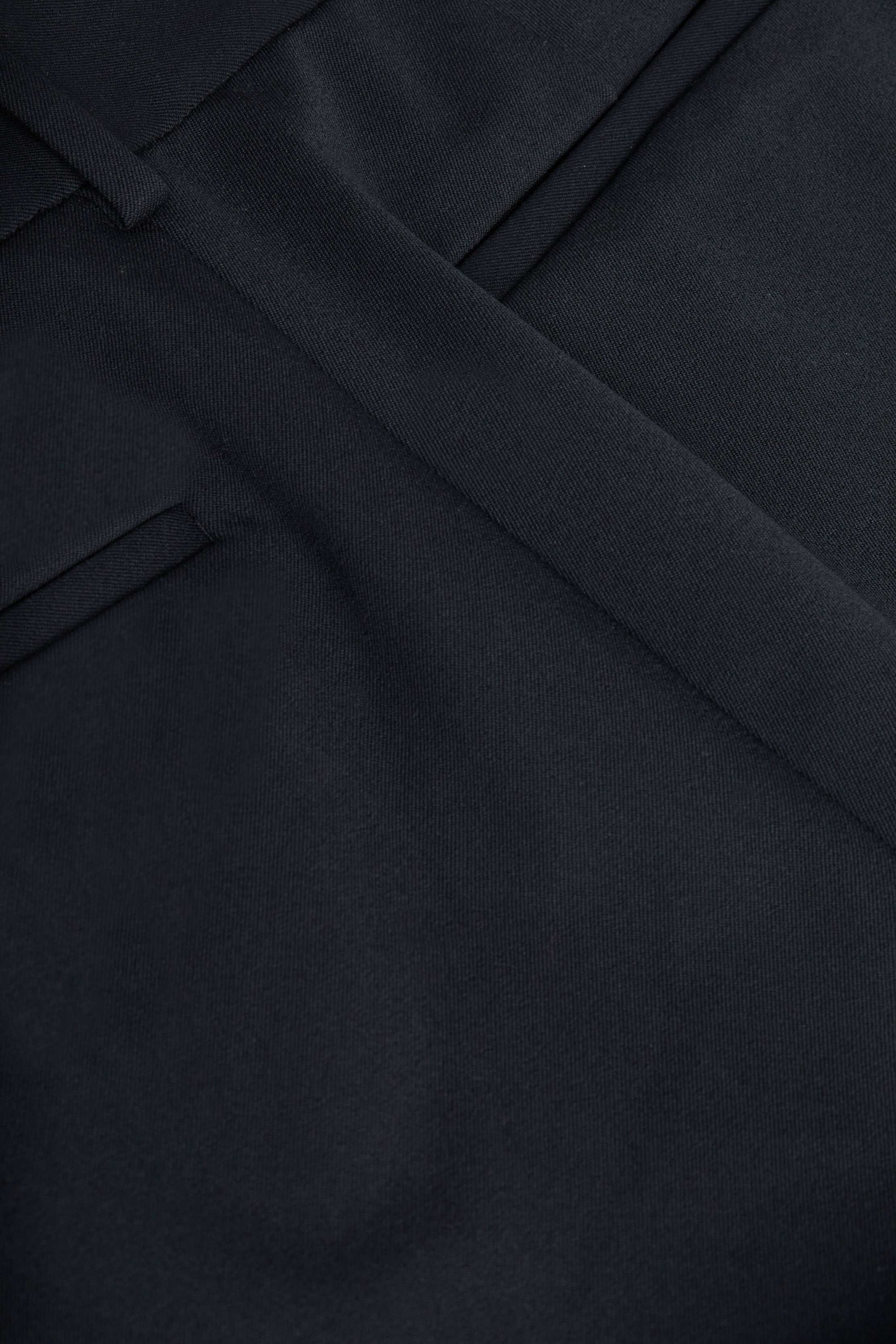 Close-up of a dark navy suit jacket, showcasing a lapel, pocket, and neatly pressed seam with fine fabric texture. Crafted from four-way stretch suiting, this style pairs perfectly with women’s trousers or the Pilar Wide-Leg Pant for a polished look.