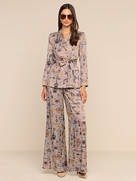 A woman stands against a plain white background wearing sunglasses and a matching printed suit, featuring the Pilar Wide-Leg Pant in a brown houndstooth pattern and a belted blazer.