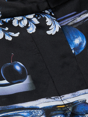 Close-up of the Pilar Silk Wide-Leg Pant by L'AGENCE, showcasing dark fabric adorned with a porcelain print of blue and white ornamental leaves, a blue plum, and abstract shapes for a refined, artistic look.