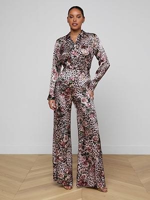 A woman poses confidently in a minimal room, wearing the Pilar Silk Wide-Leg Pant with a rose cheetah print and high rise, her hand on her hip.