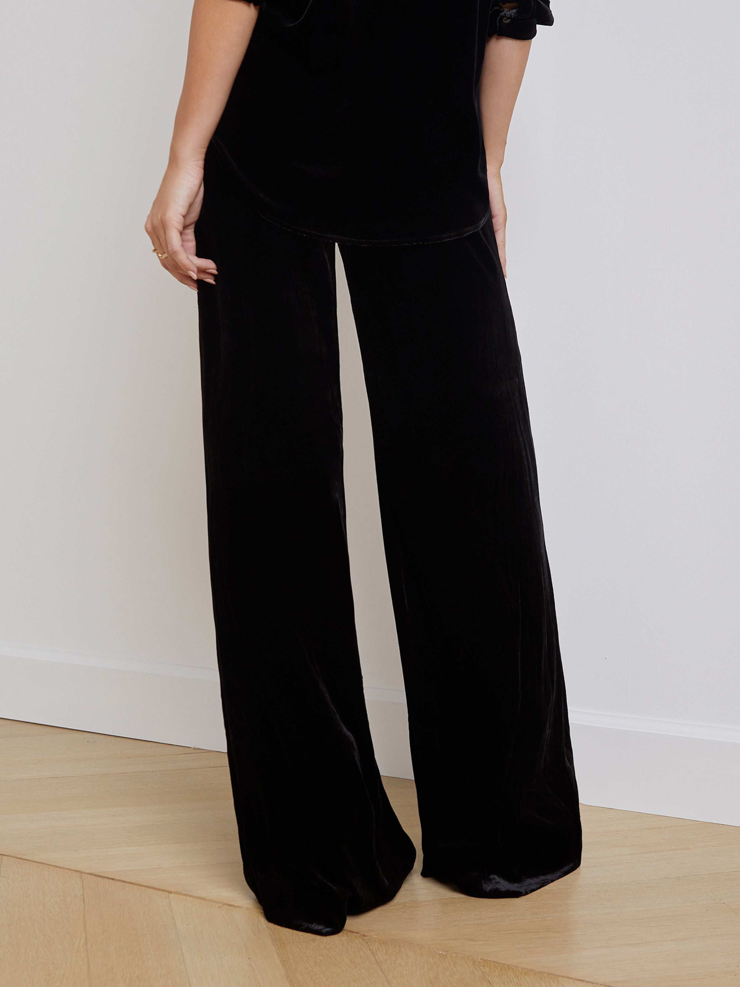 A person wearing the Pilar Velvet Wide-Leg Pant in black with a matching top, shown from mid-torso down against a plain light background.
