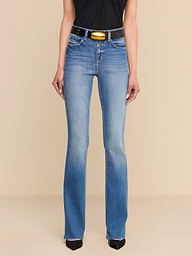 Person wearing Ruth Straight-Leg Jean in light blue—crafted from premium stretch denim—paired with a black sleeveless top, a black belt featuring a gold buckle, and black pointed shoes, standing against a plain white background.