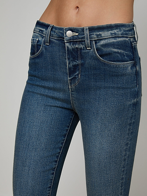 A close-up of a person wearing the Ruth Straight-Leg Jean, featuring high-waisted indigo denim with faded details and a raw hem, and showcasing the waistband, pockets, and midriff.